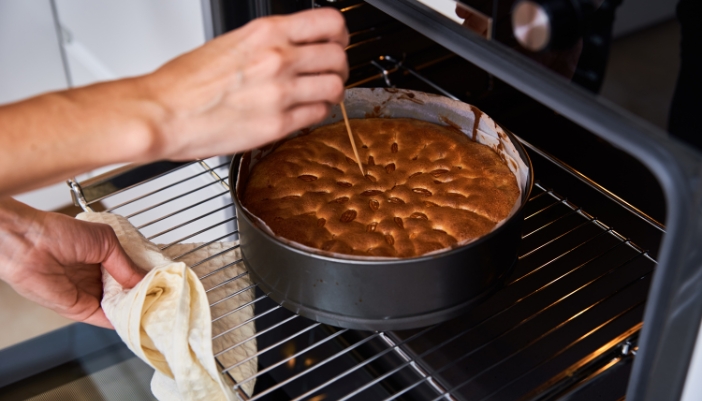 Closeup of someone doing the toothpick test on their cake fresh from the oven