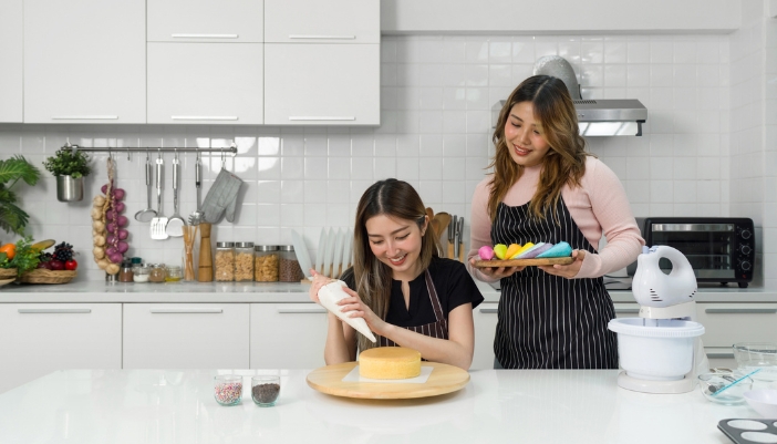 Two friends about to decorate a cake fresh from the oven