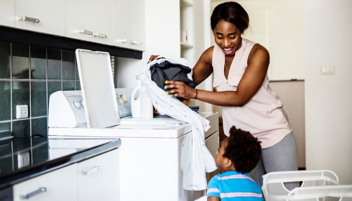 A mother and son unload a top-load washing machine together.