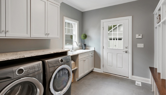 A empty laundry room with gray walls and metallic gray laundry appliances.