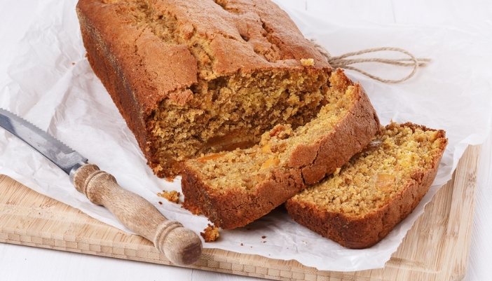 A loaf of pumpkin bread with a few pieces sliced off and a knife resting beside it.