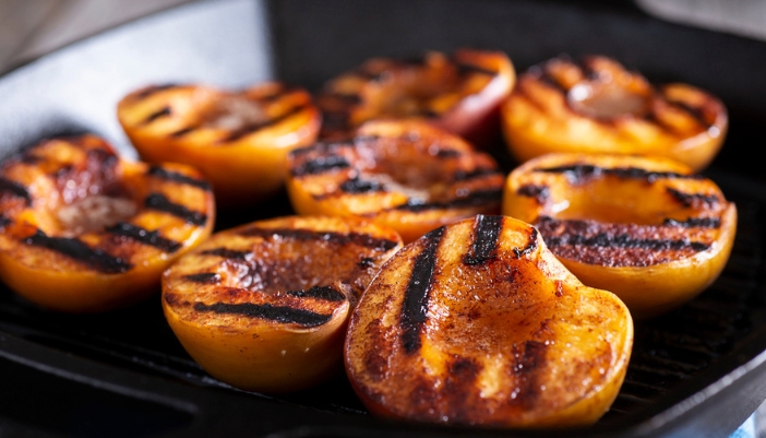 A grill pan of cooked peaches.