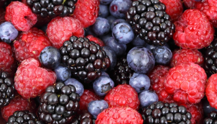 A close-up of a pile of raspberries, blueberries, and blackberries.
