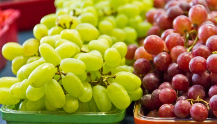 Containers of green grapes and red grapes side-by-side.