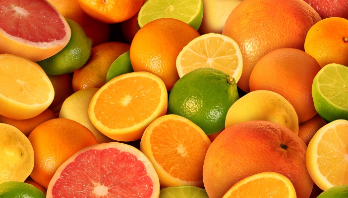 A close-up of a variety of citrus fruits, some cut in half and some not.
