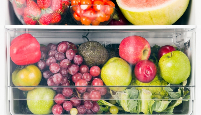 A close-up of the interior of a refrigerator crisper drawer with fruits and veggies inside.