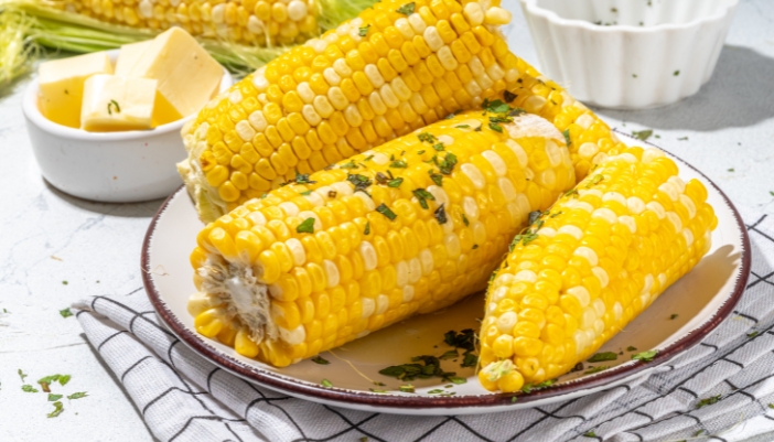 Corn on the cob ready to serve on a white plate.