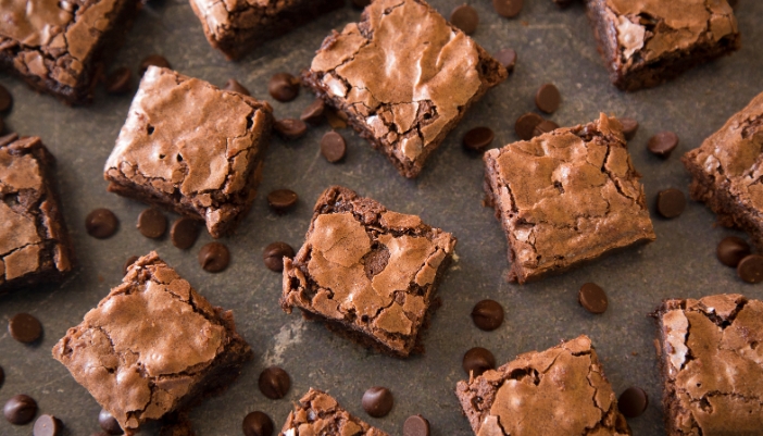 Sliced squares of brownie are laid on a black surface.
