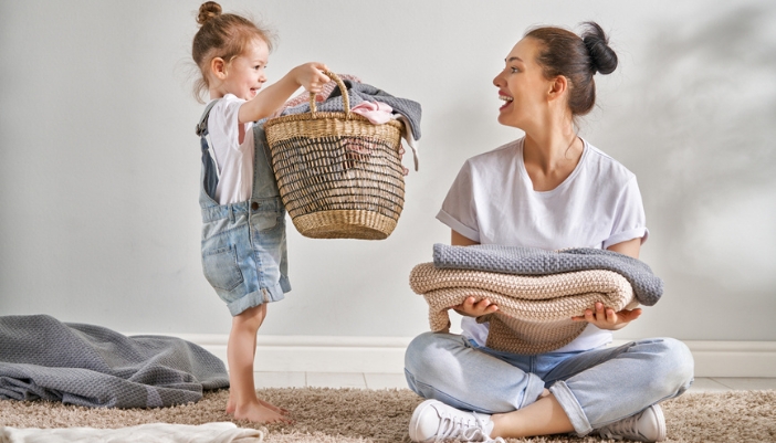 A woman and child fold laundry together at home.