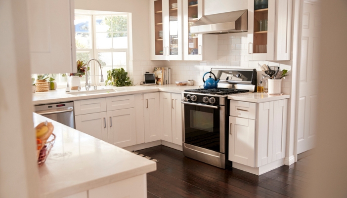 A white, neutral kitchen with a gas range featured.