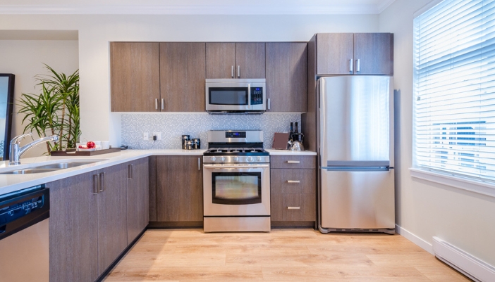 A modern kitchen with brown cabinets and stainless steel appliances.