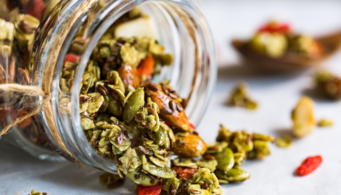A close-up of a granola mix that includes matcha, pumpkin seeds, and oats.