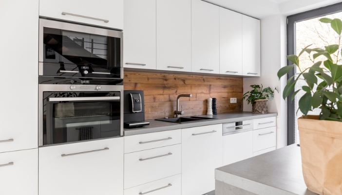 A modern kitchen with white cabinets and a stainless steel double oven