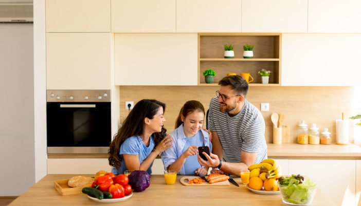 A family preps a meal together in their brightly lit modern kitchen.