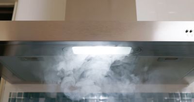 A close-up of steam being pulled into a range hood 
