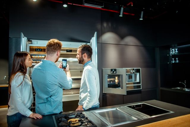 Front view of a modern kitchen showroom with a couple shopping for a fridge