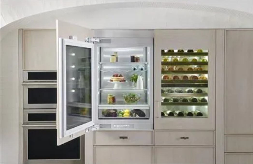 Glass door refrigerator ajar next to a built in wine cooler