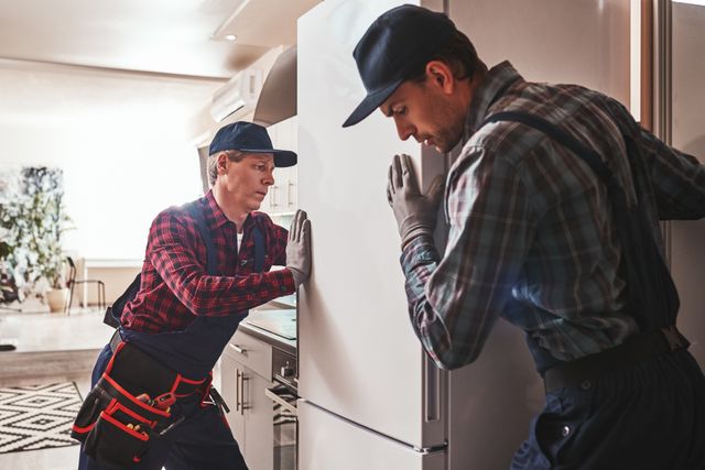View of two men installing a refrigerator in a modern kitchen