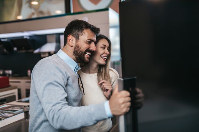 View of a couple shopping for a refrigerator and smiling