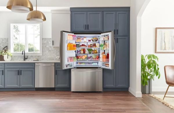 Counter depth refrigerator with French doors open in a kitchen with blue cabinets