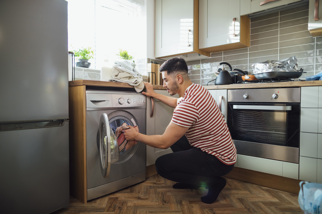 man adding towels to washer