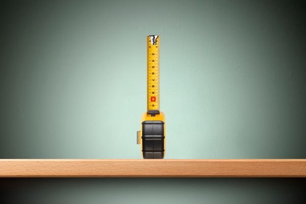 A semi-extended tape measure against a green wall 