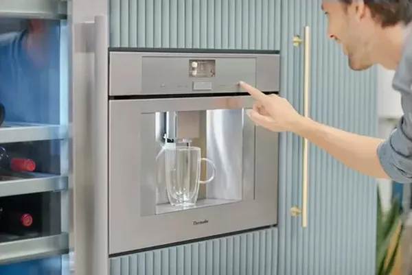 A person making a drink using the Thermador TCM24PS coffee maker 