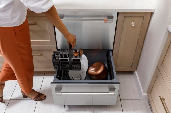 A woman loading in the Cafe CDD420P2TS1 drawer dishwasher  