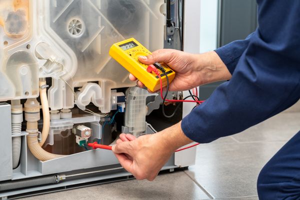 A person using a multimeter on a dishwasher