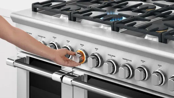 A person cleaning the Fisher & Paykel OR30SDG4X1 range