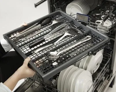 A person removing the Viking FDWU524 dishwasher third rack