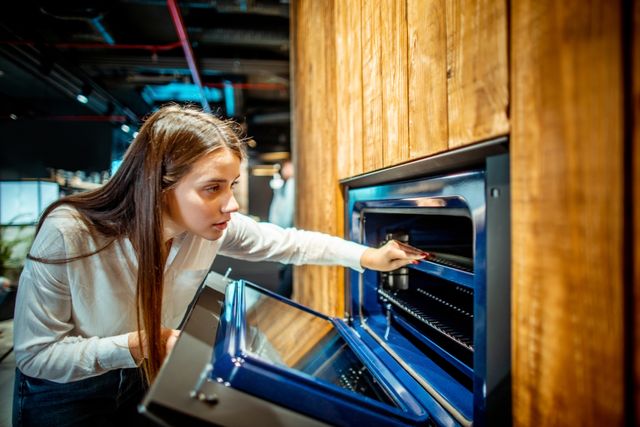 Front view of a woman shopping for a wall oven in an appliance store