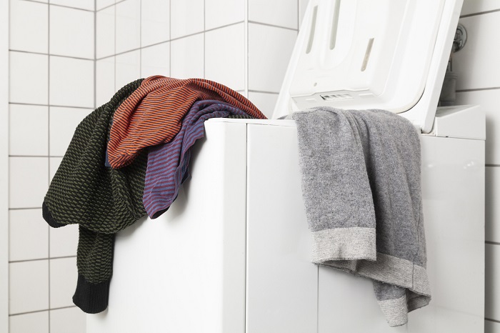 Top-loaded washer filled with an assortment of clothes.