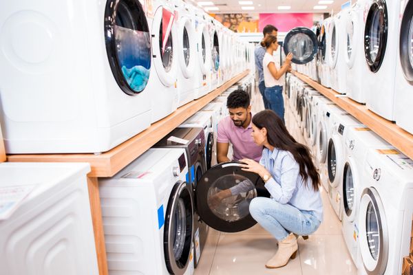 Buyers examining front load washers in a store