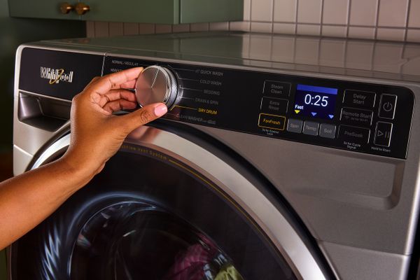 A person adjusting the dial on the Whirlpool WFW5720RR washer
