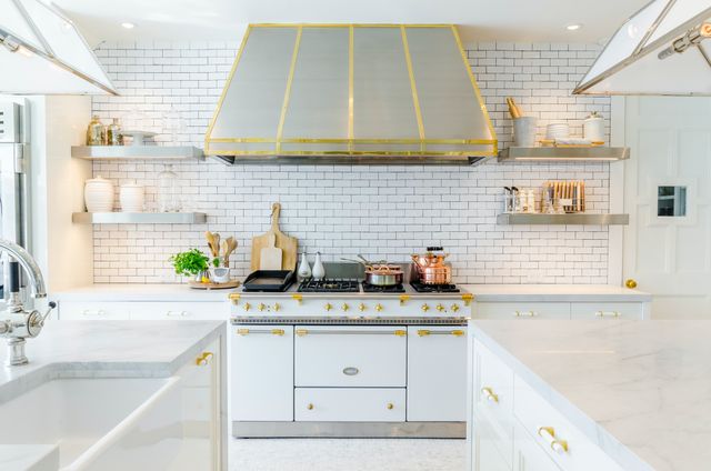 front view of a white range with gold accents in a white kitchen