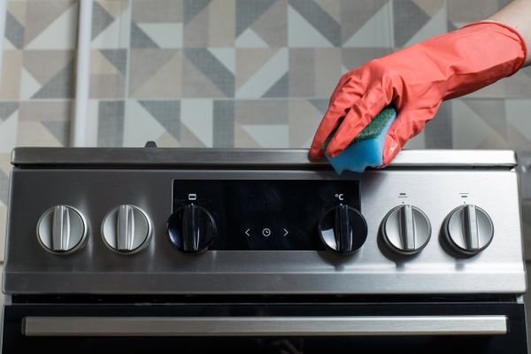 A person using a scrubber to clean an oven 
