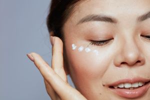 A close-up of a woman applying eye cream 