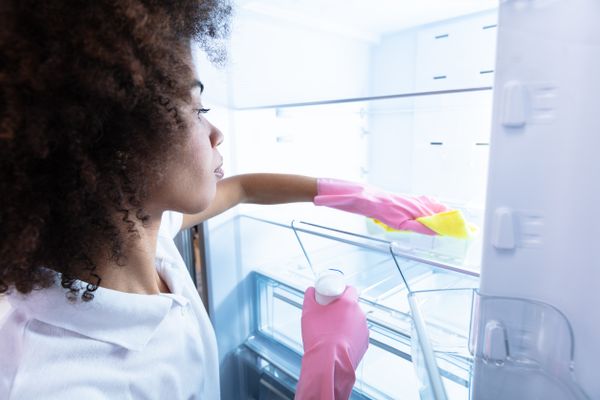 A close-up of a woman cleaning a refrigerator 