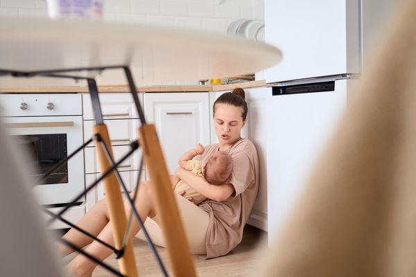 A woman holding a sleeping baby on the kitchen floor 