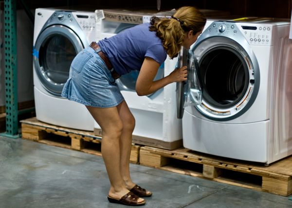 A woman inspecting a front load washer at a warehouse 