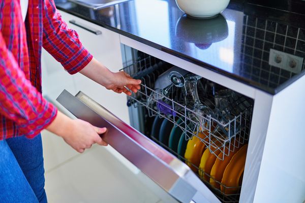 A woman opening a dishwasher