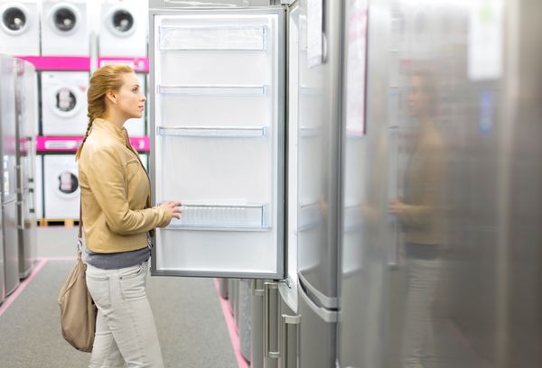 A woman reviewing a refrigerator in a store