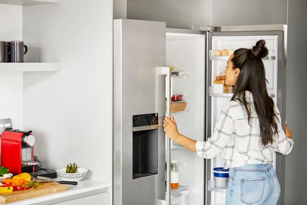 A woman looking into a French door counter depth refrigerator 