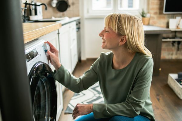 A woman smiling while using a front load washer 