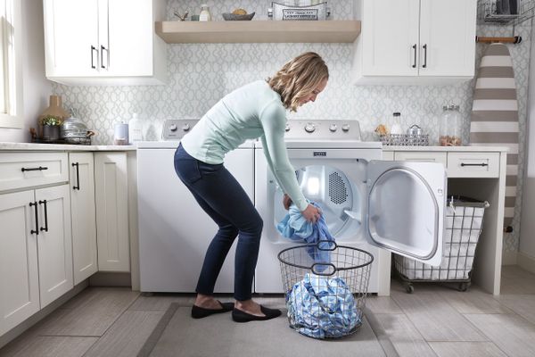 A woman unloading clothes from a Maytag dryer