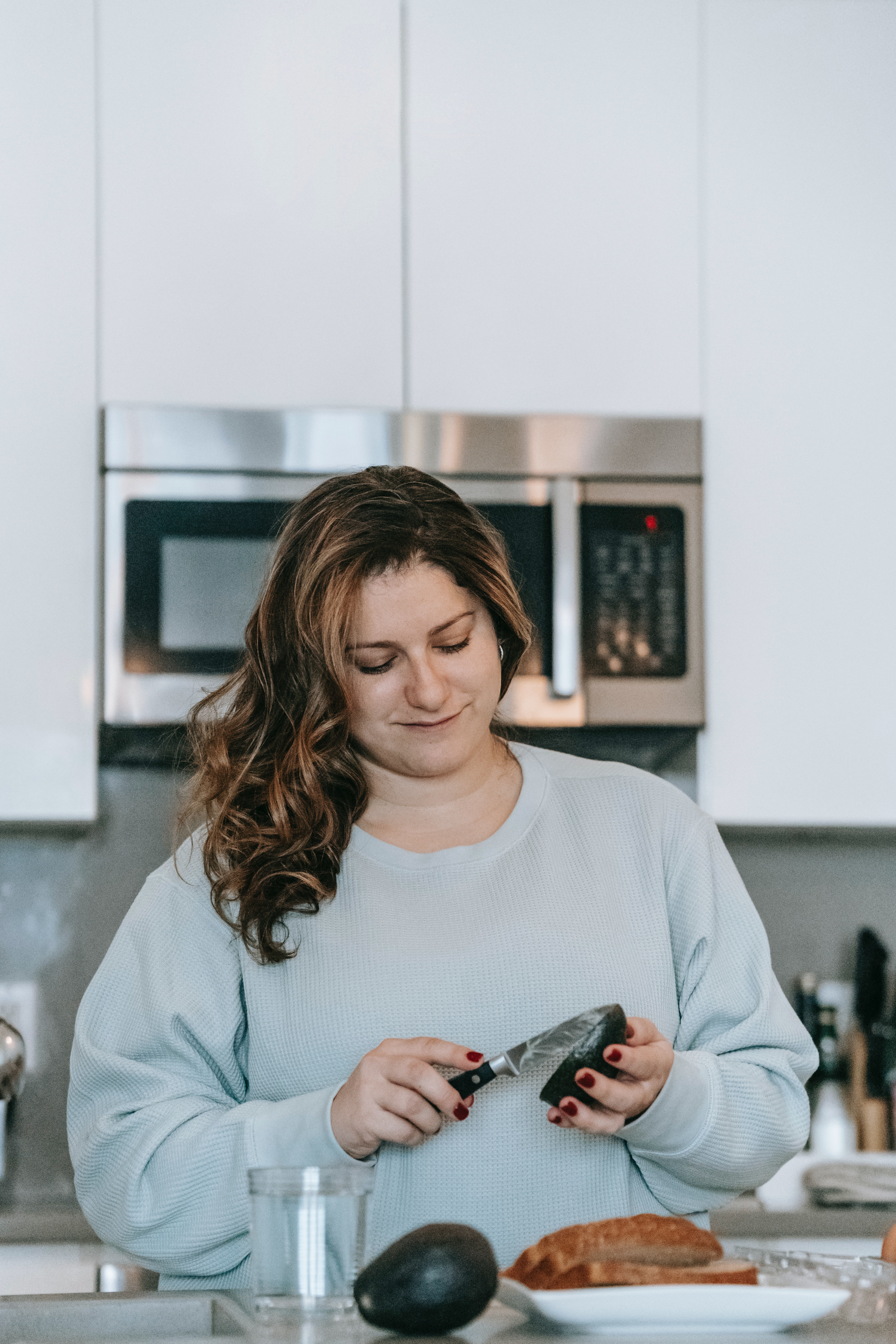 Woman Cutting Avocado in Kitchen