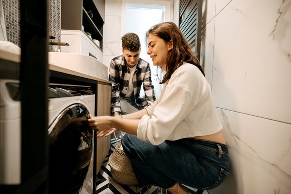A young man and woman doing laundry in a small space
