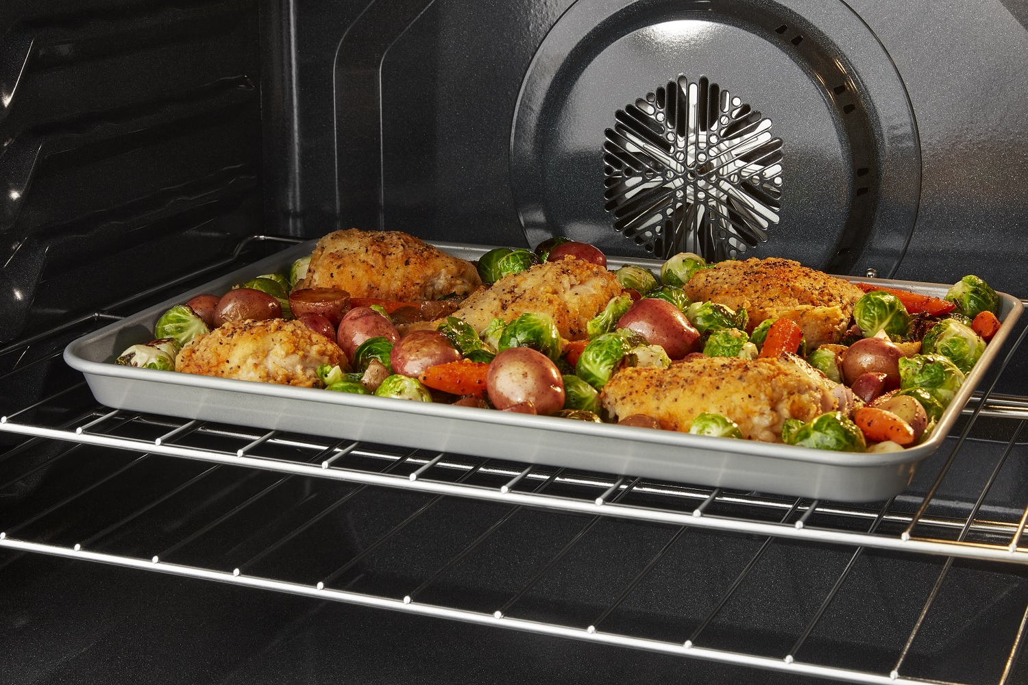 interior shot of Whirlpool oven showcasing convection fans and tray of roasted vegetables