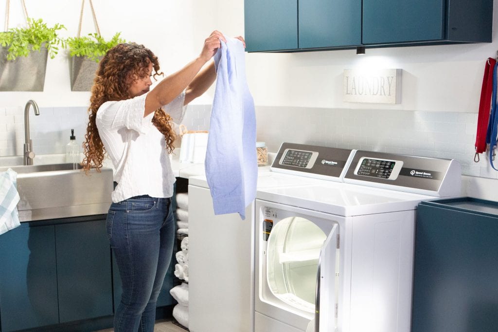 Woman taking an article of clothing out of a Speed Queen dryer 